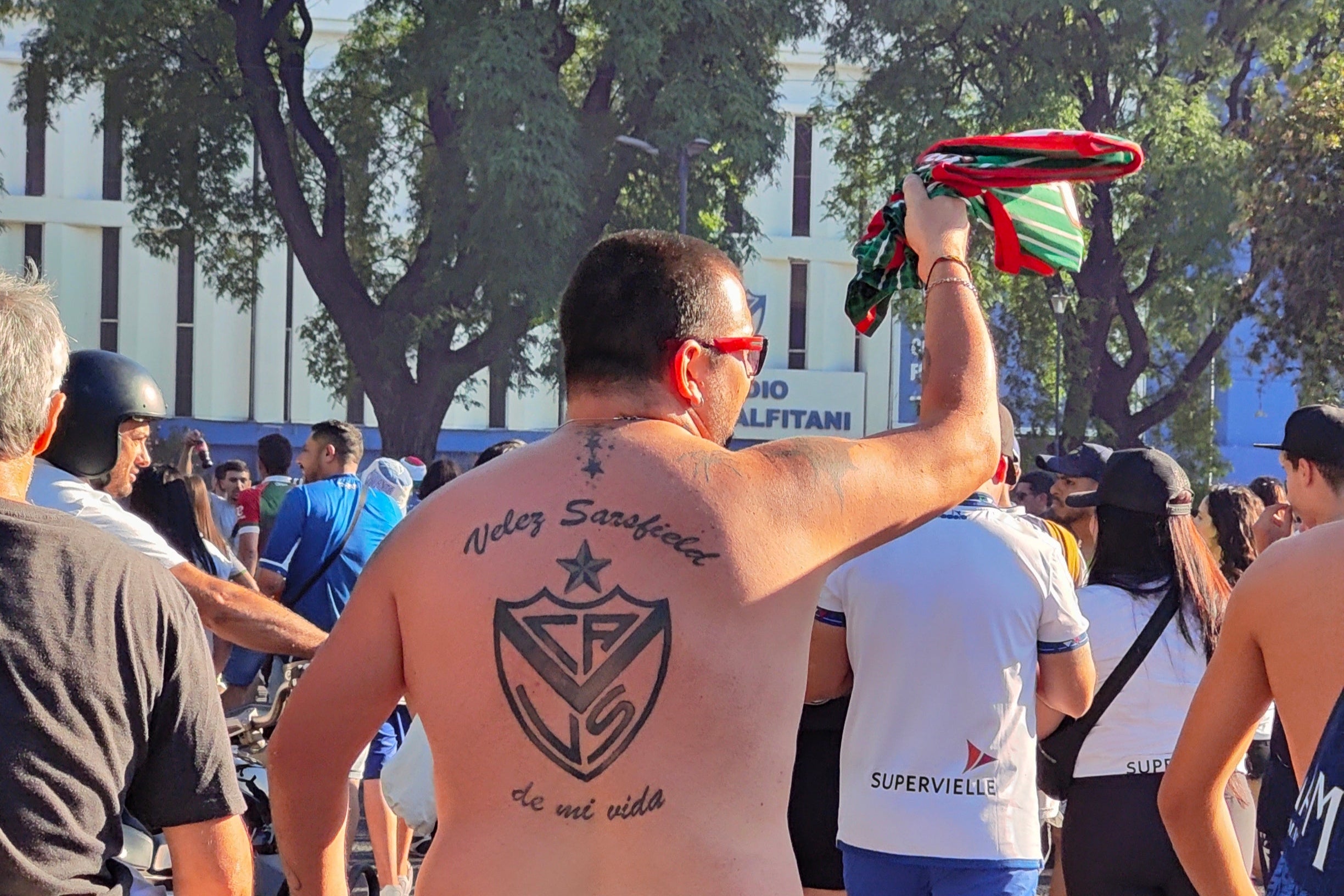 Man with Vélez Sarsfield tattoos on his back walking among a crowd of people at the Jose Amlafitani stadium in Liniers.