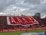 Large red and white banner with 'A.A.A.J.' in the Diego Armando Maradona stadium during an Argentinos Juniors match.