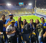 Group of Pibe de Barrio Matchday experience guests posing for a photo in the Bombonera stadium with blue and yellow colours.