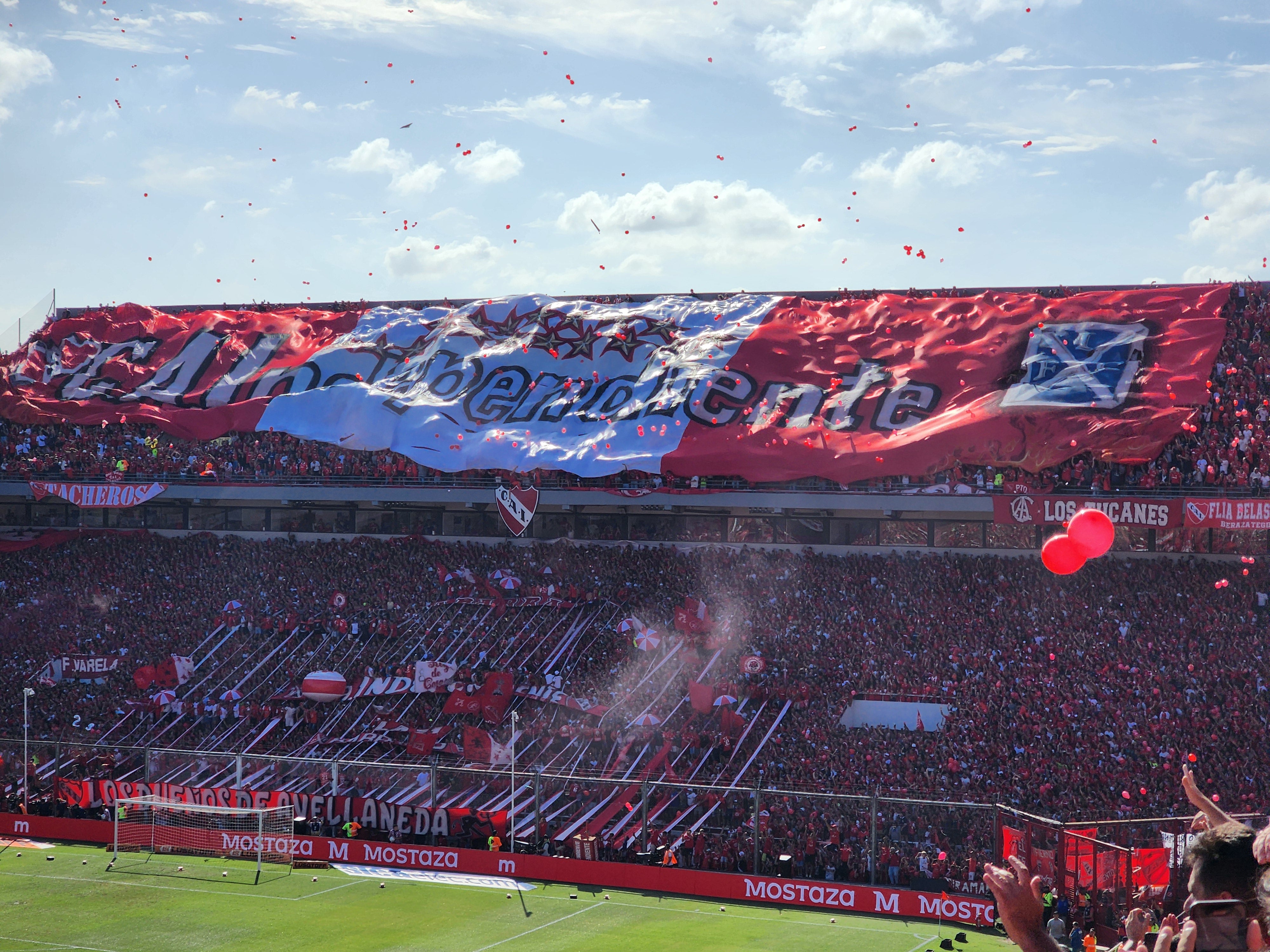 Independiente fans unfurl a large telón banner in the popular of the Ricardo Bochini stadium